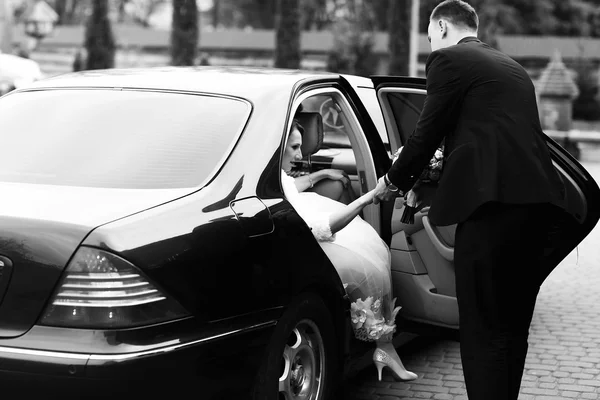 Vőlegény menyasszony, hogy hagyja el a fekete Mercedes segít — Stock Fotó