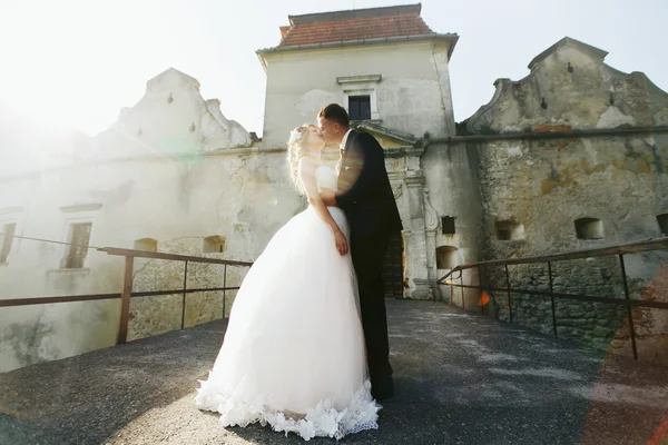 Brudgummen pussar en brud innan ingången till den gamla borgen — Stockfoto