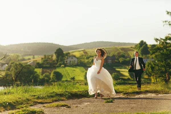 Bruden och brudgummen kör längs byvägen njuter av sommaren weath — Stockfoto