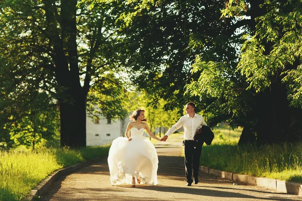 Nygifta kör längs sökvägen i parken på kvällen — Stockfoto