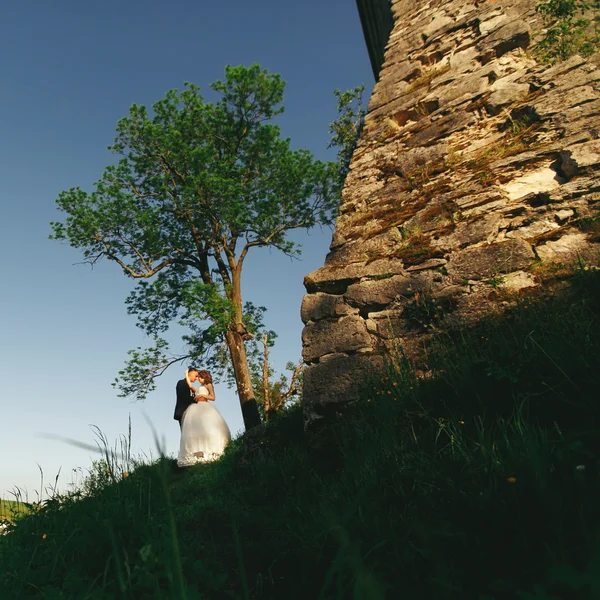 Juste marié se tenir derrière un mur de château de pierre — Photo