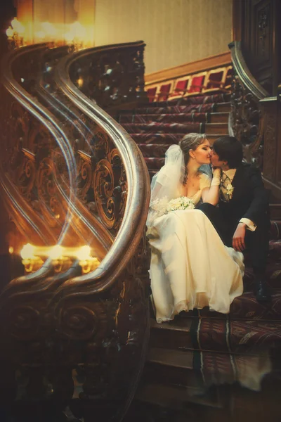 Recién casados se sienta en las viejas escaleras de madera — Foto de Stock