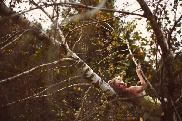 Femme en robe jaune se trouve sur la branche de l'arbre — Photo