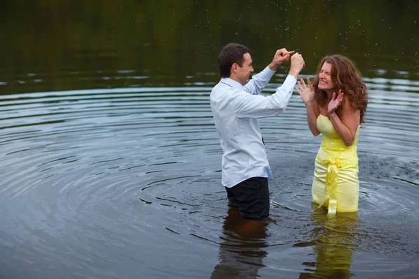Dáma ve žluté šaty a muž v obleku hře s vodou v jezeře — Stock fotografie