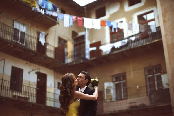 Recém-casados se beijam na frente da casa velha com varandas — Fotografia de Stock