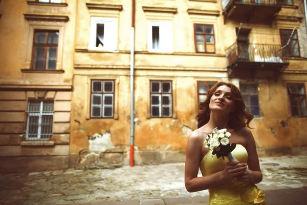 Novia en vestido amarillo sueña despierto en algún lugar de la ciudad vieja — Foto de Stock