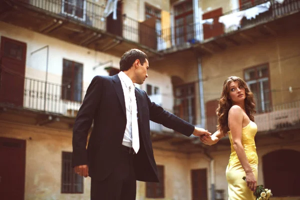 Novia en vestido amarillo se vuelve hacia el novio sosteniendo su mano — Foto de Stock