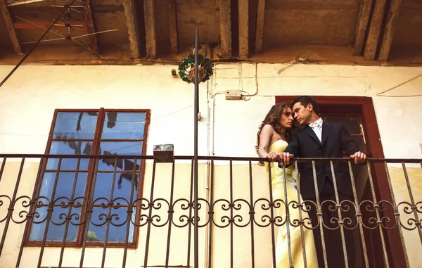 Мужчина и женщина в желтом стоят задумчиво опираясь на балкон — стоковое фото