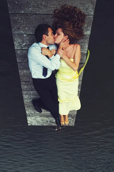 Мужчина целует женщину, лежащую на мосту — стоковое фото