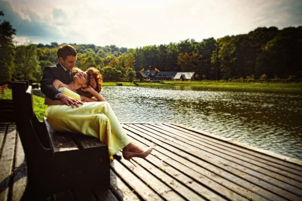 Dame en robe jaune repose sur les genoux de l'homme derrière un lac — Photo