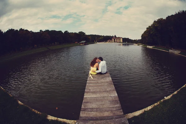 湖の橋の上に座って男と女の抱擁 — ストック写真