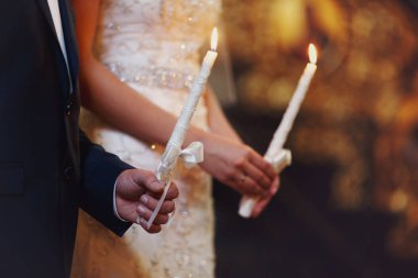 Bir evlilik çift tutun ellerinde saten RI ile beyaz mumlar