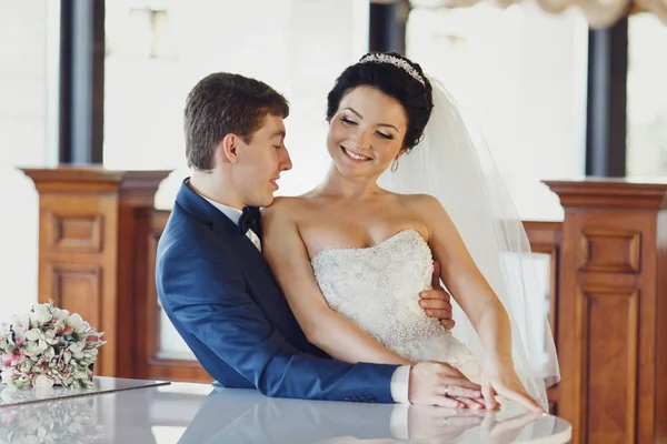 Bräutigam hält die Taille der Braut, während sie auf seinen Knien sitzt — Stockfoto