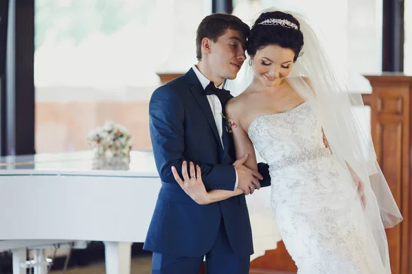 Bruden lutar sig på en brudgummens axel stående framför en pia — Stockfoto