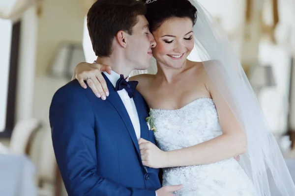 Bräutigam berührt die Wange der Braut und hält sie zärtlich in seinen Armen — Stockfoto