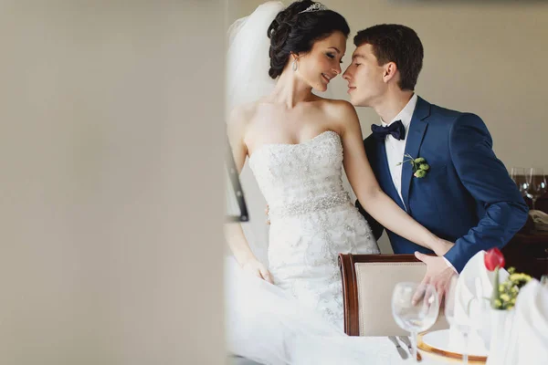 Groom reaches a delicate bride's face for a kiss — Stock Photo, Image