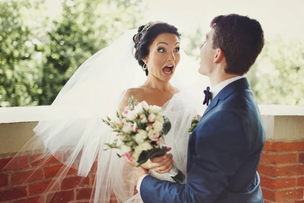 Funny bride looks shocked being hugged by a groom — Stock Photo, Image