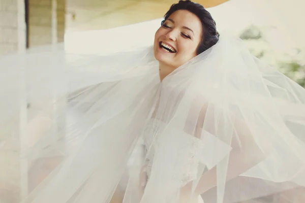 Невеста смеется, пока ветер играет с ее вуалью — стоковое фото