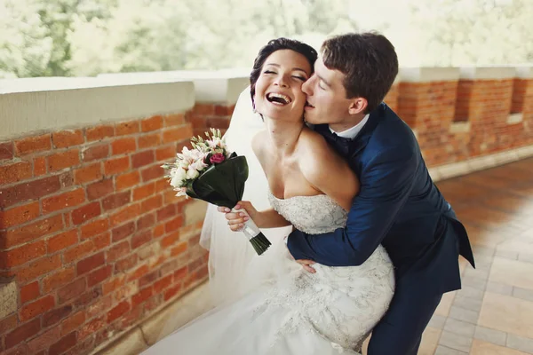 Жених кусает невесту за щеку и обнимает ее сзади. — стоковое фото