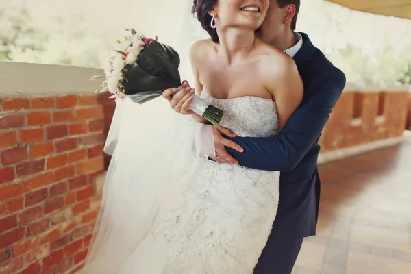 Groom kisses back of bride's neck holding her from behind — Stock Photo, Image