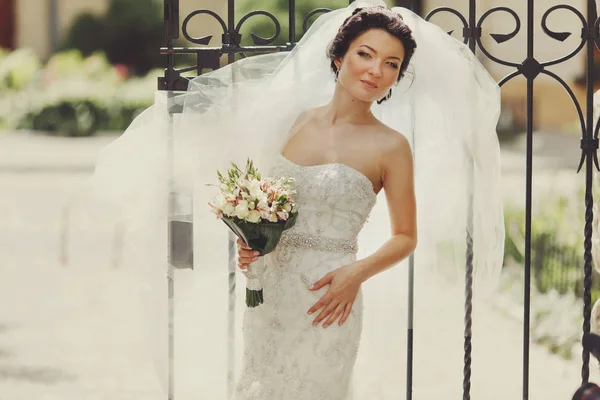 Красивая невеста позирует перед старыми воротами — стоковое фото