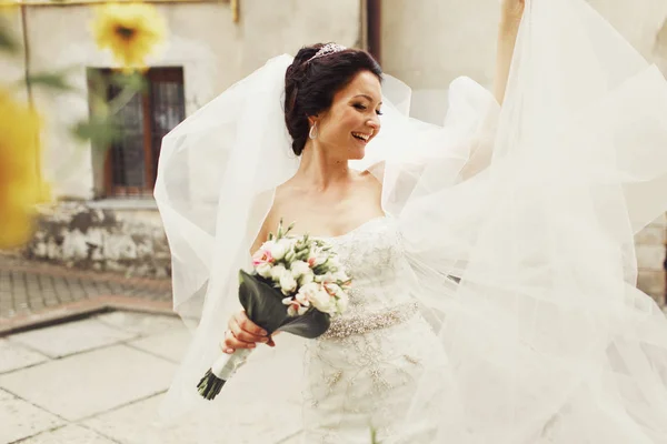 Невеста смеется, кружась вокруг своей вуали. — стоковое фото