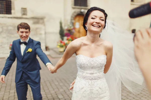 La mariée tient la main du marié marchant avec lui jusqu'au caméraman — Photo