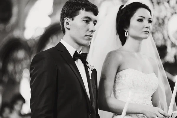 Los recién casados se ven meditando durante una ceremonia en la iglesia — Foto de Stock