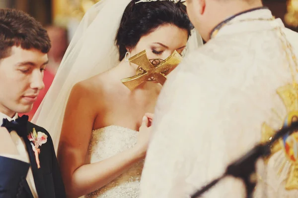 Bride kisses a holy cross in the hands of priest — Stock Photo, Image