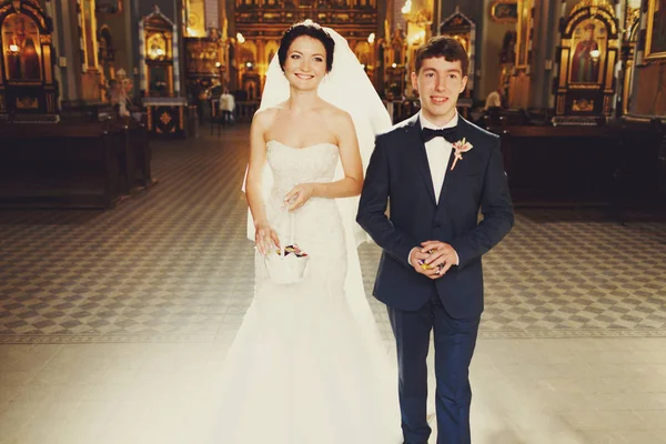 Noiva sorridente e noivo saem da igreja — Fotografia de Stock