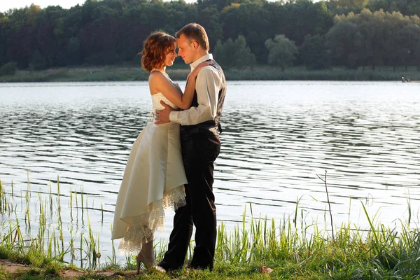 Apenas casado posando atrás da água — Fotografia de Stock