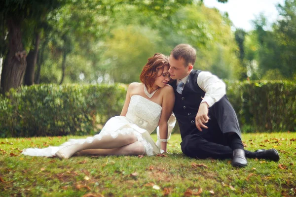 Pareja de boda descansa en el suelo verde — Foto de Stock