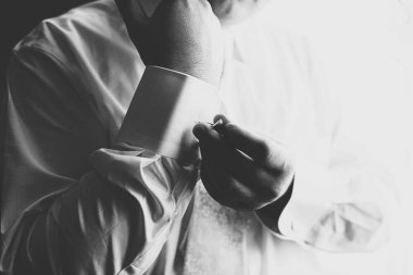 Adam bir kol düğmesi üzerinde beyaz bir gömlek bir manşet atıyor 