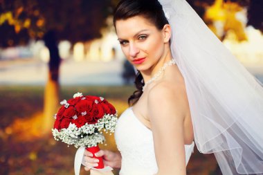 Kendinden emin bir gelin bir park boyunca akşam yürür. 