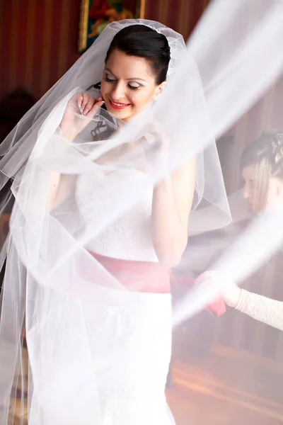 Счастливая невеста улыбается стоя в завесе — стоковое фото