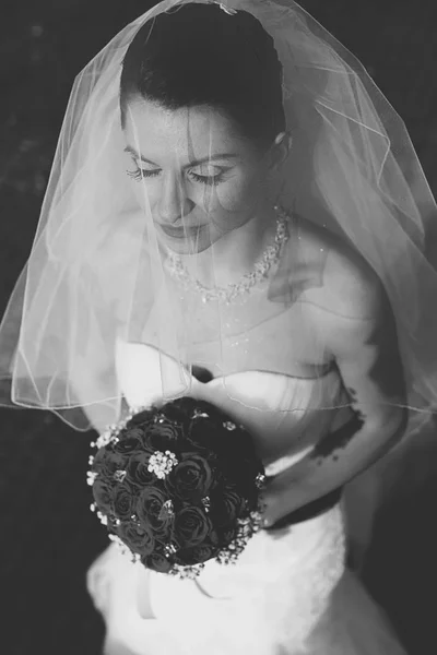 Sluier omvat een bruid permanent met gesloten ogen en een bruiloft-bouq — Stockfoto