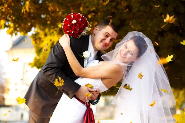 Feuilles d'or tombent sur un sourire jeunes mariés — Photo