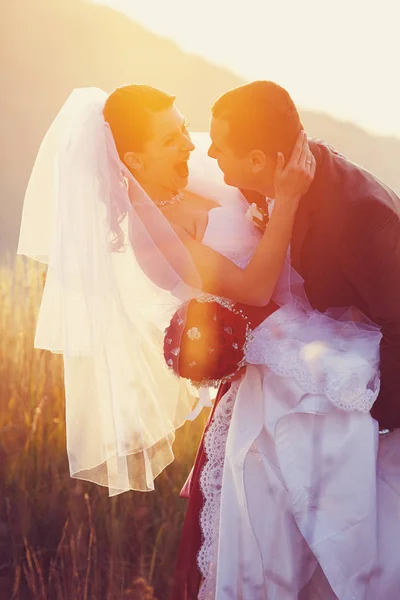 Os recém-casados riem em algum lugar no campo à noite — Fotografia de Stock