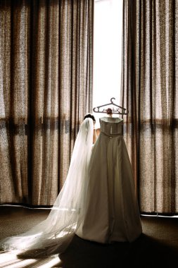 Gelin peçe içinde bir gelinliğin tutuyor