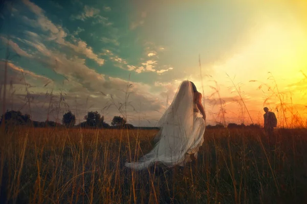 Bruden går mot en fästman under lysande himmel under solen — Stockfoto
