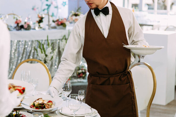 Свадебный официант обслуживает стол с едой
