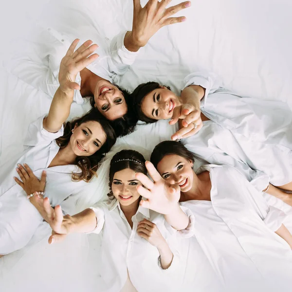 Chicas felices con una novia en la cama blanca —  Fotos de Stock