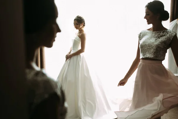 Sensual bride next to the window with her friends