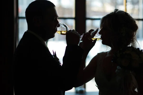 Eine Silhouette von Braut und Bräutigam, die einen prickelnden Champagner trinkt — Stockfoto