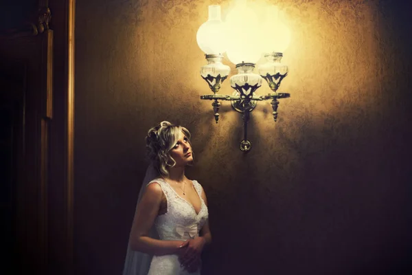 Premurosa sposa sta sotto il vecchio lampadario d'epoca — Foto Stock
