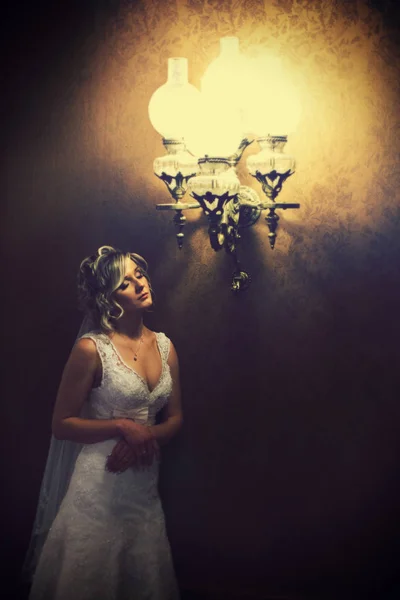 Light of vintage chandelier illuminates a pretty bride — Stock Photo, Image