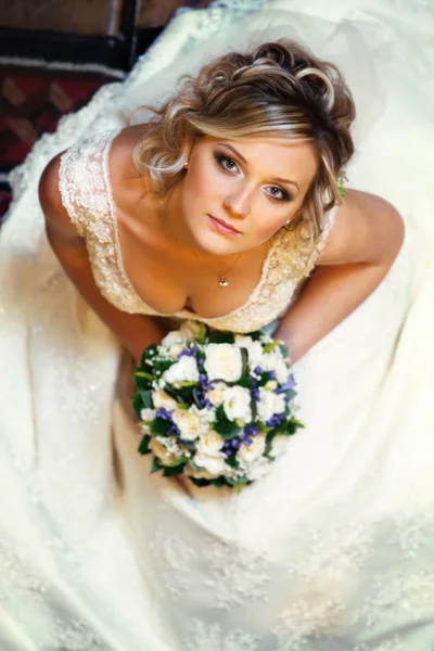 Hübsche Braut blickt nachdenklich auf und hält einen Strauß Rosen in der Hand — Stockfoto