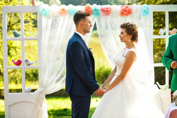 Novias de pie cerca del arco de la boda — Foto de Stock