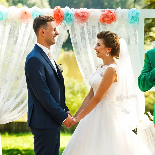 Noivas de mãos dadas perto do arco do casamento — Fotografia de Stock