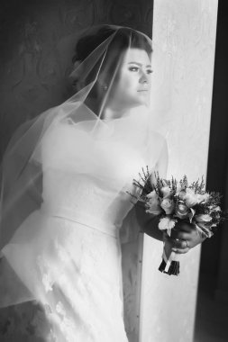 Düşünceli gelin ile kaplı bir peçe bir duvara eğilir 